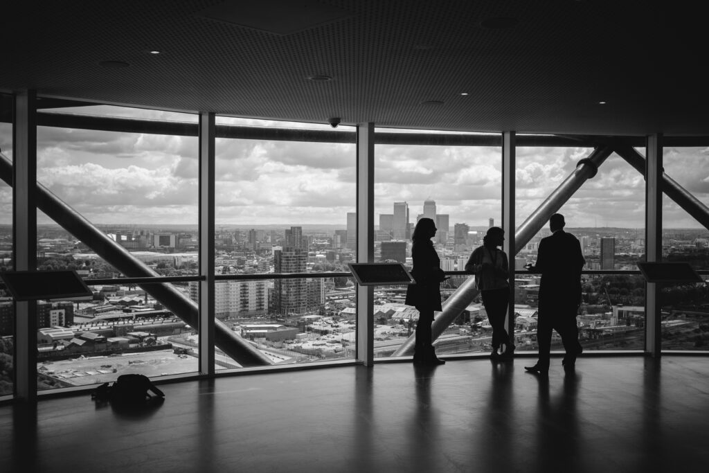 Employees standing in a city office with large window view of urban landscape.